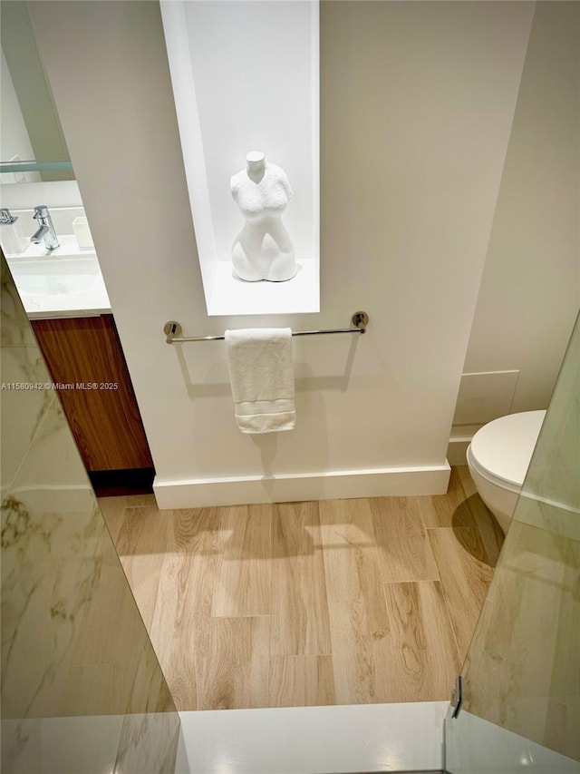 bathroom with toilet, hardwood / wood-style floors, and vanity