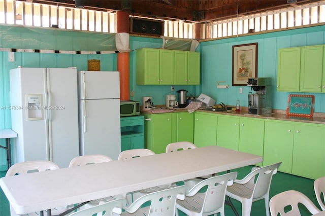 kitchen featuring sink, white refrigerator with ice dispenser, white fridge, and green cabinets