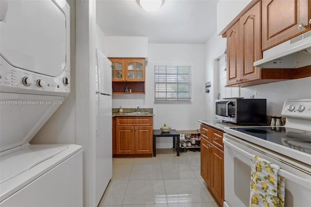 kitchen with stacked washer and clothes dryer, white appliances, light tile floors, and sink