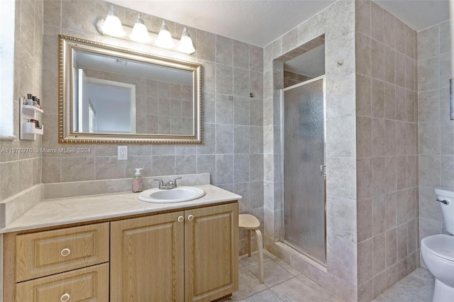 bathroom featuring vanity, toilet, tile flooring, and tile walls