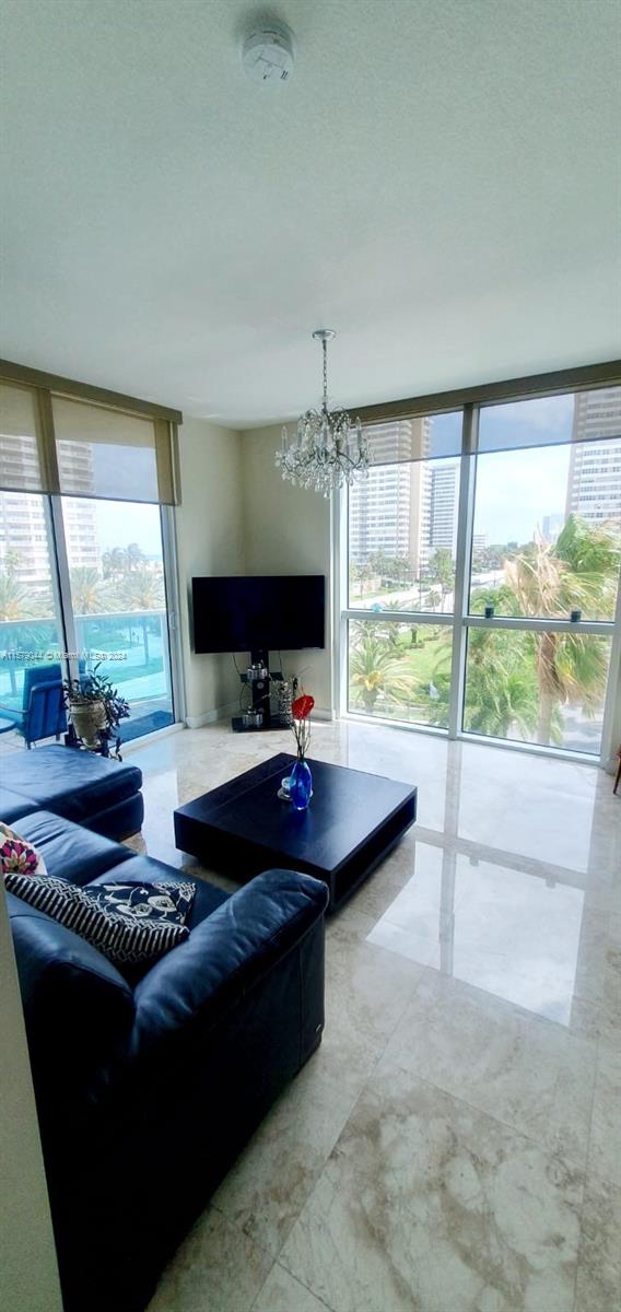 tiled living room with a wall of windows and an inviting chandelier