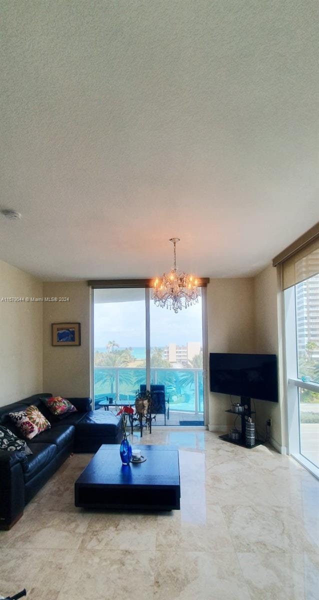 living room featuring a textured ceiling, expansive windows, an inviting chandelier, and tile flooring