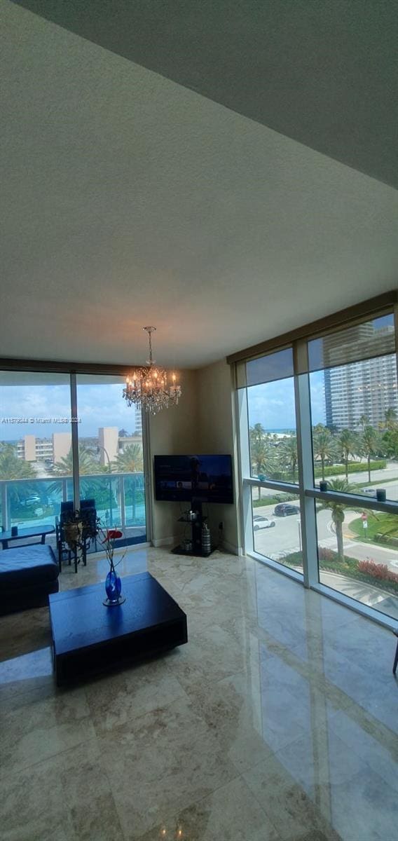 unfurnished living room with an inviting chandelier, tile flooring, and a wall of windows