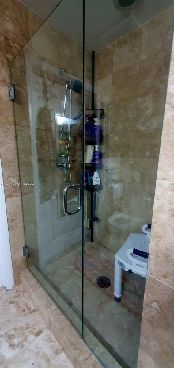 bathroom featuring tile floors, tile walls, an enclosed shower, and toilet