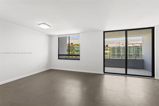 unfurnished room featuring a wall of windows and tile patterned floors