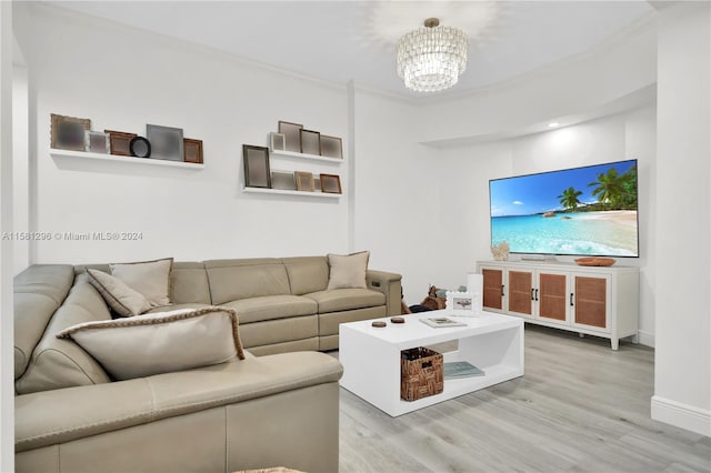 living room featuring crown molding, light hardwood / wood-style flooring, and a notable chandelier