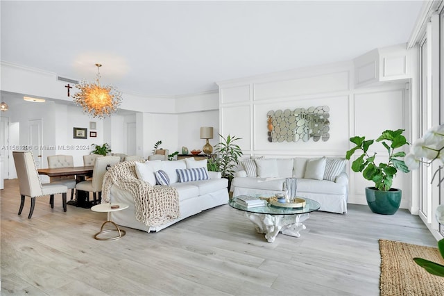 living room featuring ornamental molding, a notable chandelier, and light hardwood / wood-style flooring