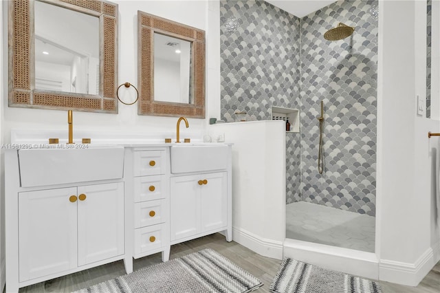 bathroom with tiled shower and dual vanity