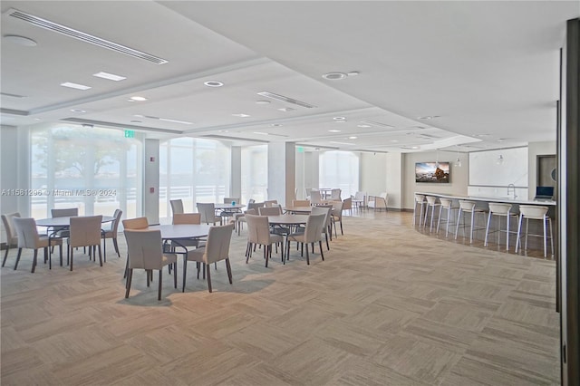 carpeted dining room with expansive windows and a raised ceiling