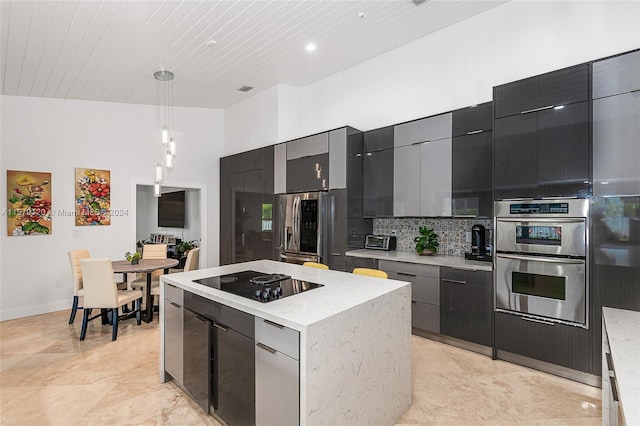 kitchen with a center island, hanging light fixtures, tasteful backsplash, a towering ceiling, and appliances with stainless steel finishes