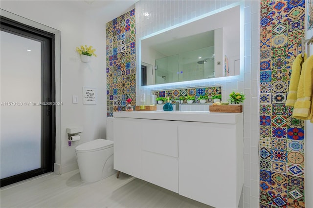 bathroom featuring vanity, toilet, a shower with door, and tile walls