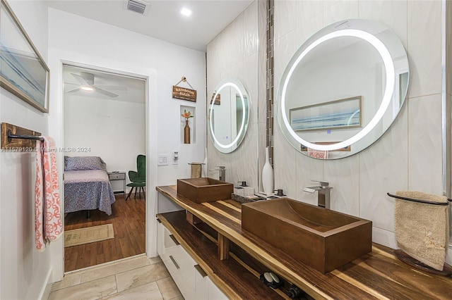 bathroom with hardwood / wood-style floors, vanity, ceiling fan, and tile walls