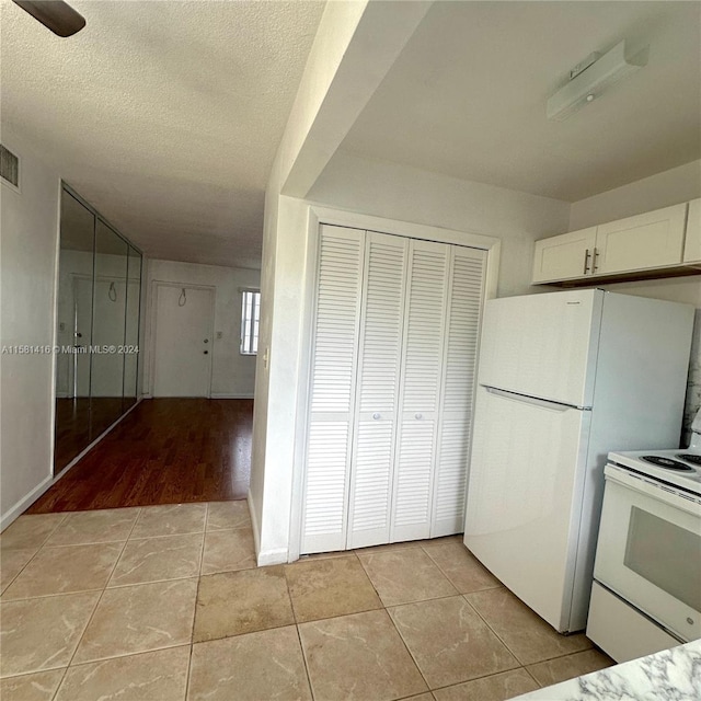 kitchen with white cabinetry, white appliances, a textured ceiling, and light hardwood / wood-style floors