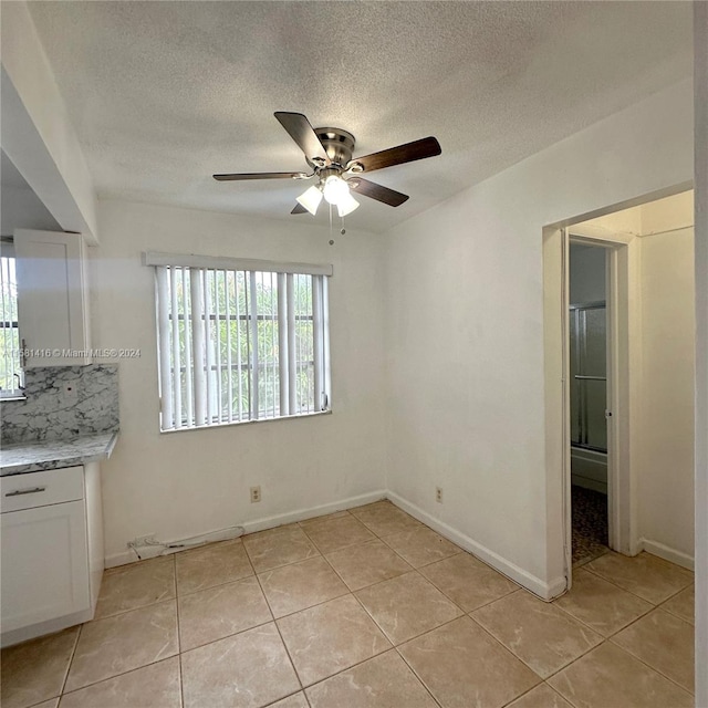 interior space with ceiling fan, a textured ceiling, and light tile patterned floors