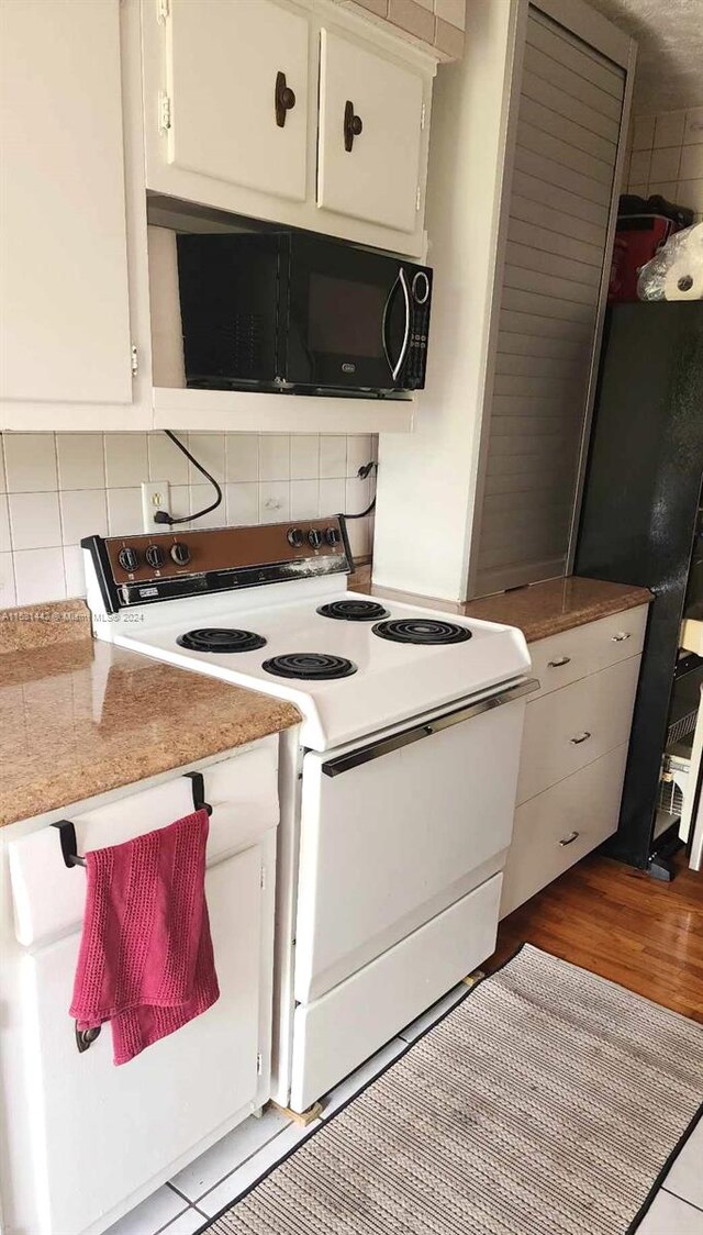 kitchen with backsplash, white cabinets, black appliances, and light wood-type flooring