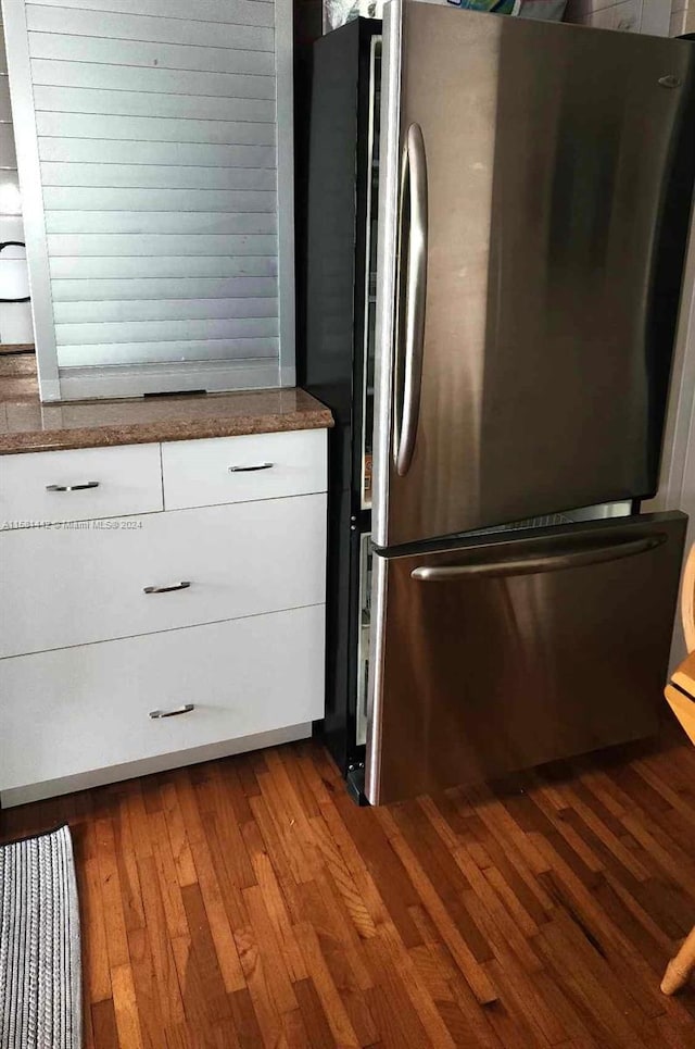 kitchen featuring white cabinetry, stainless steel fridge, and hardwood / wood-style floors