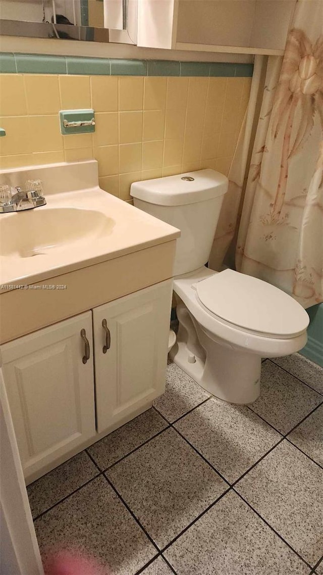 bathroom with tasteful backsplash, toilet, vanity, and tile walls