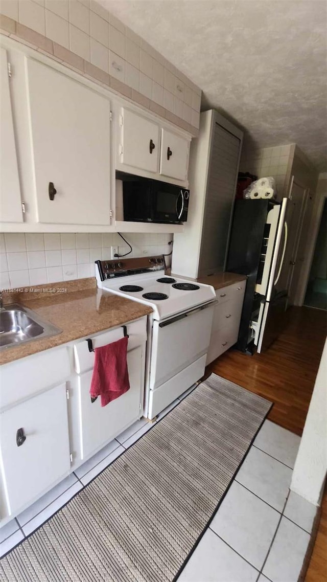 kitchen with backsplash, white range with electric cooktop, white cabinets, and stainless steel refrigerator