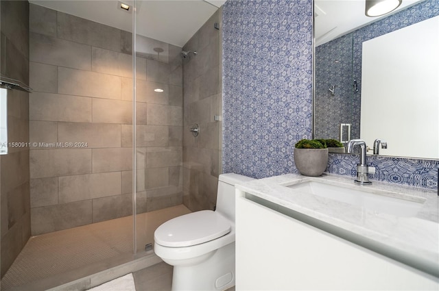 bathroom with vanity, toilet, a tile shower, and tile flooring