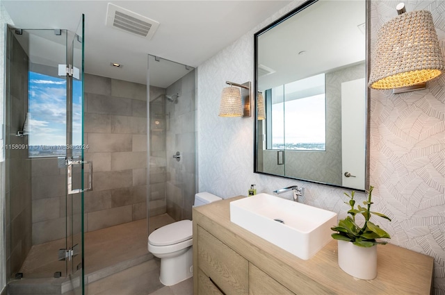 bathroom featuring a shower with door, oversized vanity, and toilet