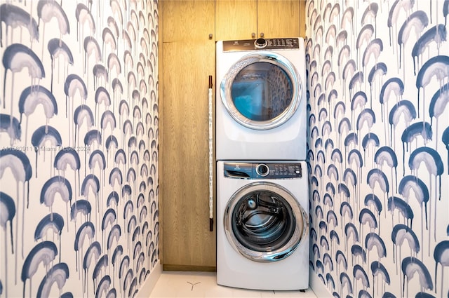 laundry area featuring stacked washer and dryer and light tile floors