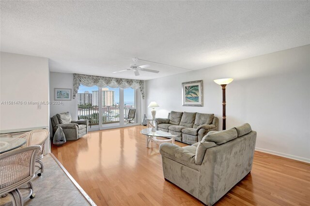 living room with a textured ceiling, light hardwood / wood-style flooring, and ceiling fan