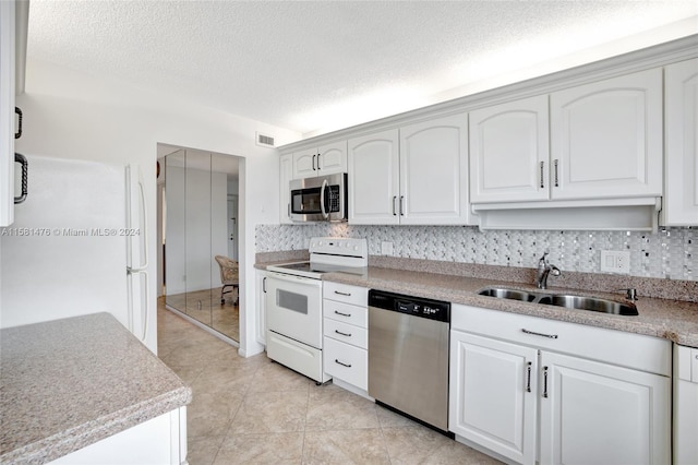 kitchen featuring a textured ceiling, backsplash, stainless steel appliances, sink, and white cabinetry