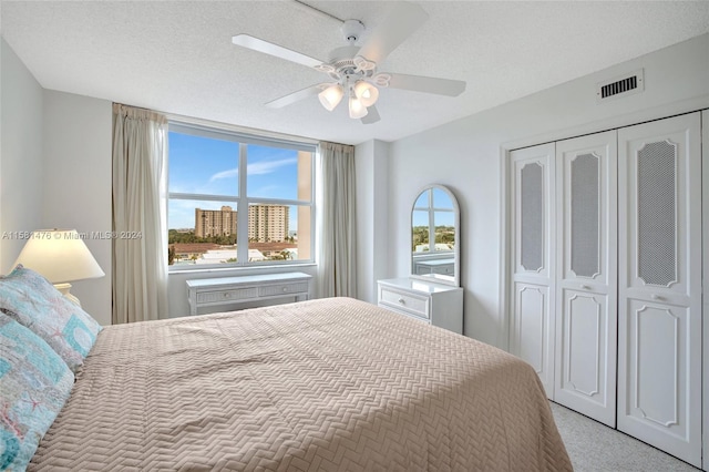 carpeted bedroom featuring a textured ceiling, ceiling fan, and a closet