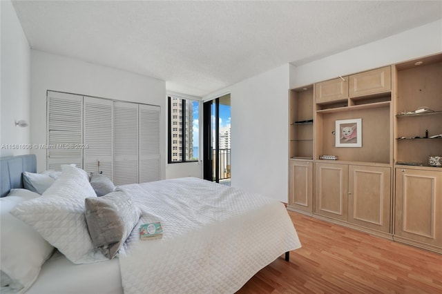 bedroom featuring a wall of windows, light wood-type flooring, a textured ceiling, and a closet