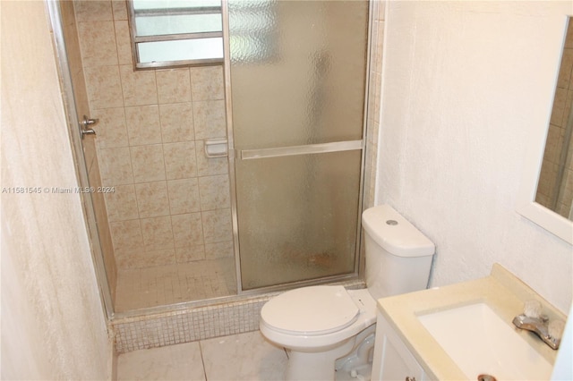 bathroom with tile patterned flooring, vanity, an enclosed shower, and toilet