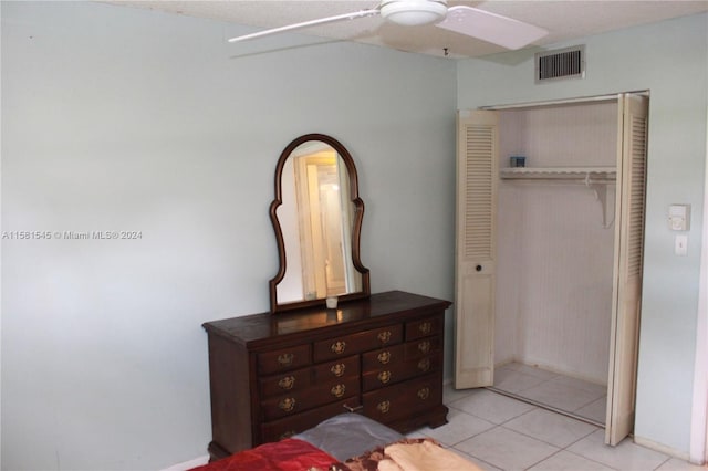 tiled bedroom with ceiling fan and a closet