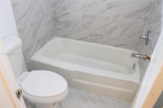 bathroom with a tub to relax in and toilet