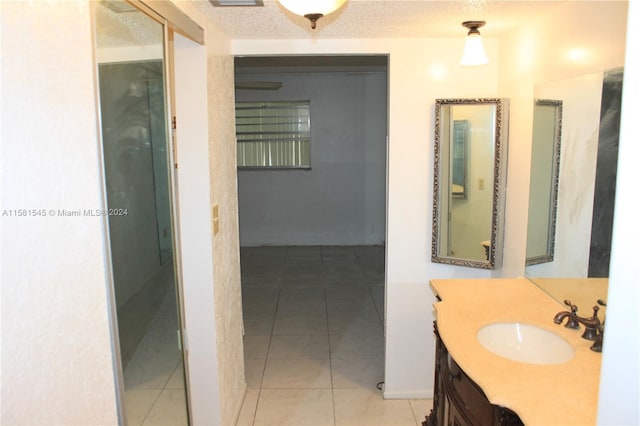 bathroom with a textured ceiling, vanity, and tile patterned floors