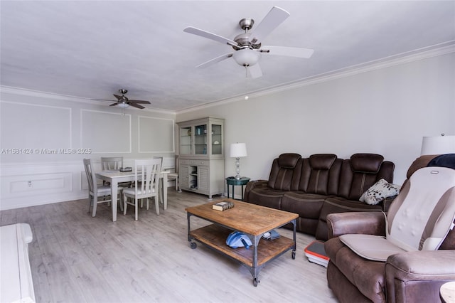 living room with crown molding, light wood-type flooring, a decorative wall, and ceiling fan