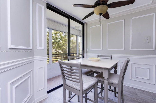 dining space with ceiling fan, a decorative wall, and crown molding