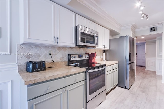 kitchen with stainless steel appliances, tasteful backsplash, light countertops, visible vents, and ornamental molding