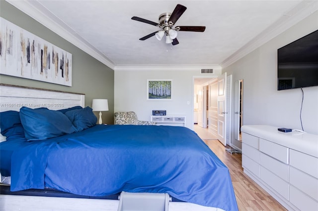 bedroom with light wood-style floors, visible vents, ornamental molding, and a ceiling fan