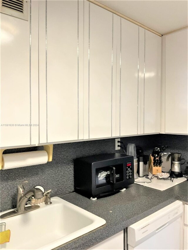 kitchen featuring backsplash, white cabinets, white dishwasher, and sink