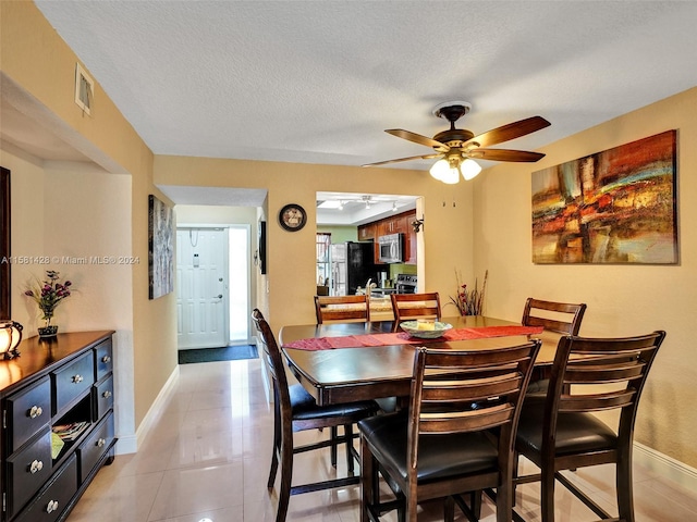 tiled dining area featuring a textured ceiling and ceiling fan