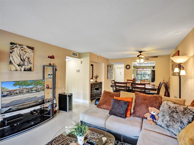 tiled living room with ceiling fan and a textured ceiling