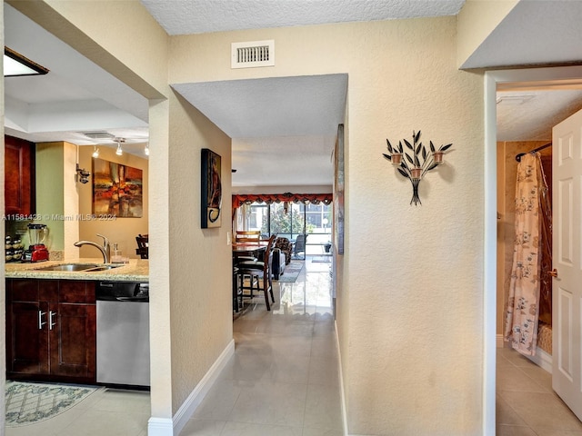 hallway featuring sink, a textured ceiling, and light tile floors