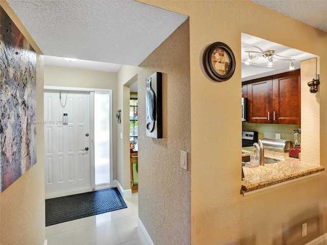 tiled foyer entrance featuring sink and a textured ceiling