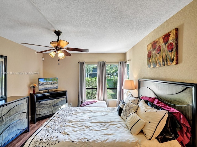 bedroom featuring dark hardwood / wood-style flooring, ceiling fan, and a textured ceiling