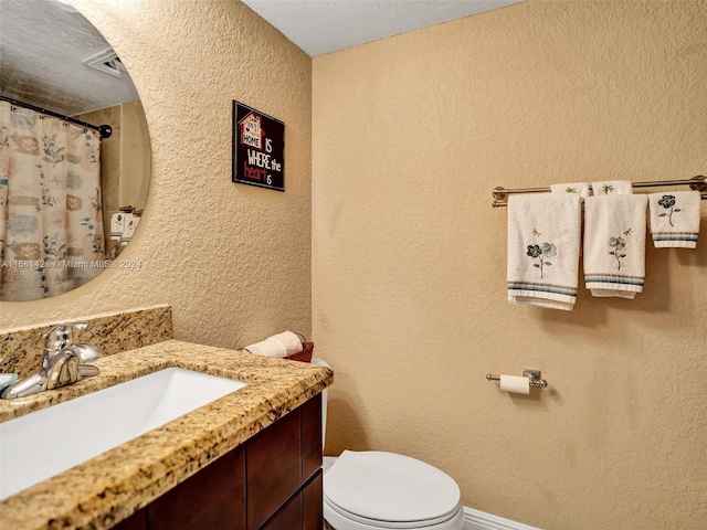 bathroom featuring a textured ceiling, toilet, and vanity