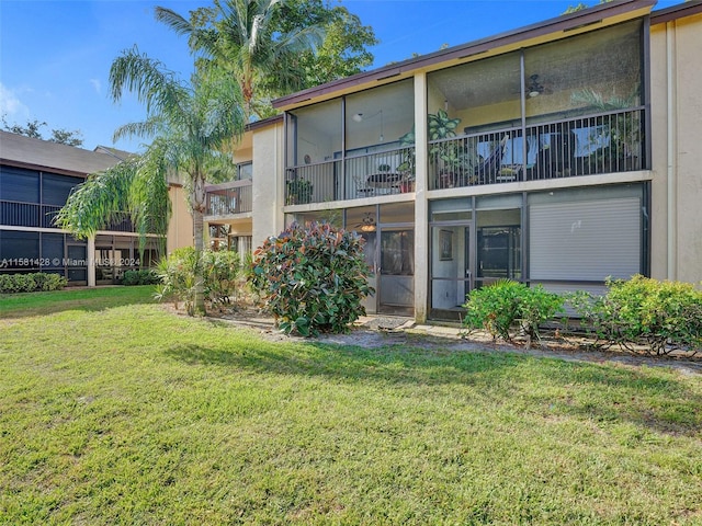 rear view of house featuring a balcony and a lawn