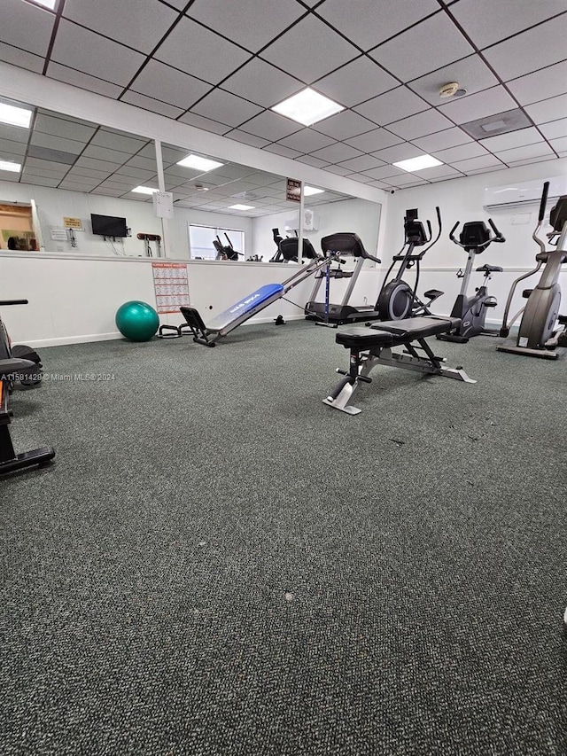 exercise room featuring a paneled ceiling and carpet flooring