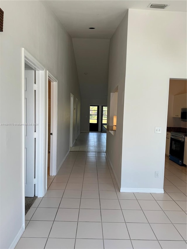 hallway with high vaulted ceiling and light tile patterned floors