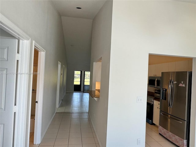 hall featuring light tile patterned floors and high vaulted ceiling