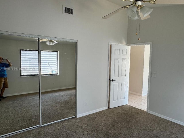 unfurnished bedroom with a towering ceiling, ceiling fan, light colored carpet, and a closet