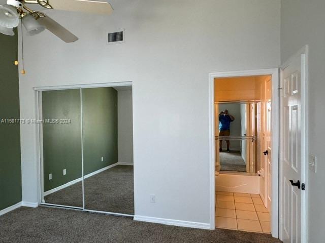 unfurnished bedroom with a closet, tile patterned flooring, connected bathroom, and ceiling fan